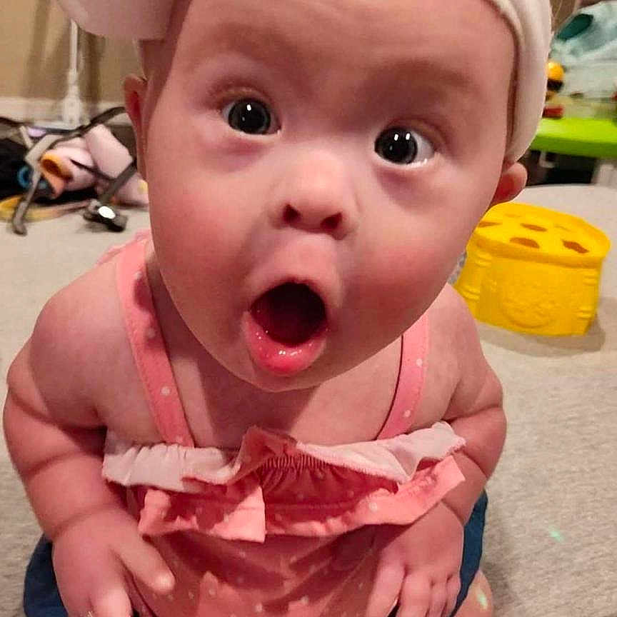 Brooklynne is registered to the contest to win money with this photo: baby, background, bow, carpet, child, cute, denim_shorts, expression, floor, headband, indoor, infant, open_mouth, person, pink_clothing, sitting, surprised, toy, white_shoes, wide_eyes