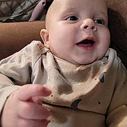 Marcell is registered to the contest to win money with this photo: baby, infant, smile, face, hand, clothing, moon_pattern, stars_pattern, cozy, couch, indoor, person, skin, happiness, portrait, cute, child, closeup, expression, warm