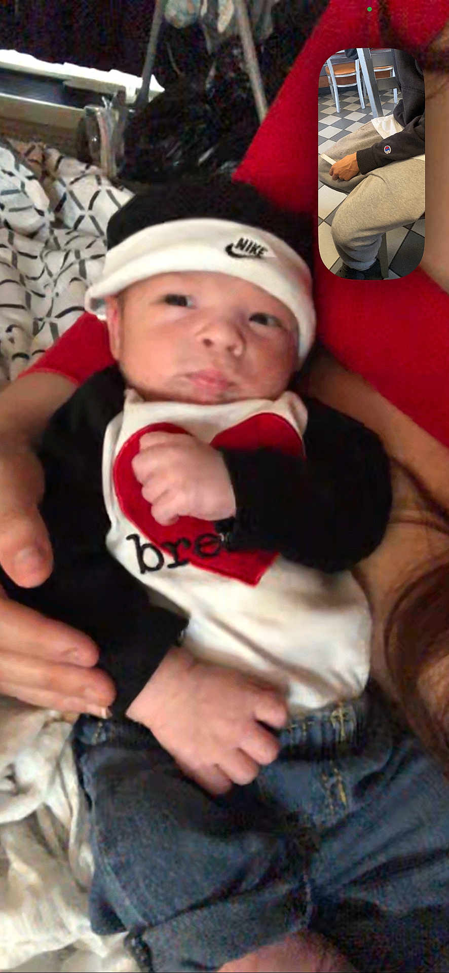 Elijah joined the competition — help win amazing prizes! baby, infant, newborn, hat, headband, bib, heart, nike, fist, hands, jeans, denim, person_holding, bed, blanket, patterned_bedding, indoor, portrait, screenshot, picture_in_picture