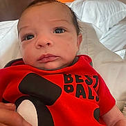 Elijah joined the competition — help win amazing prizes! baby, infant, newborn, face, eyes, mouth, nose, red_shirt, cartoon_print, hand, bedding, pillow, bed, indoor, closeup, skin, hair, curious_expression, person, portrait