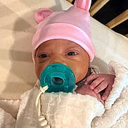 Zuri joined the competition — help win amazing prizes! baby, newborn, pacifier, pink_hat, blanket, crib, wooden_bars, hand, face, infant, clothing, sleepwear, cute, resting, indoors, soft_texture, baby_accessory, closeup, portrait, child
