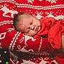 Atticus is registered to the contest to win money with this photo: baby, sleeping, red_clothing, festive_sweater, reindeer_pattern, arms, hand, holiday_lights, bokeh, indoor, portrait, child, cozy, warm, closeup, person, christmas, seasonal, soft_light, cute