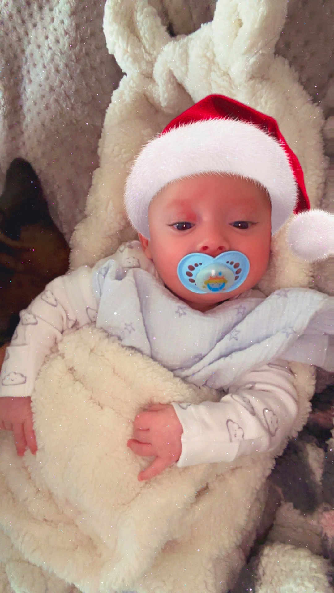 Jack joined the competition — help win amazing prizes! baby, infant, pacifier, santa_hat, blanket, soft_texture, sleepy, cute, cozy, indoors, child, portrait, warm, wrapped, hand, clothing, holiday, festive, resting, young