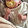 Jack is registered to the contest to win money with this photo: baby, infant, pacifier, blanket, medical_tape, clothing, wrapped, hand, fist, face, skin, newborn, soft_texture, comfort, bed, sleepwear, resting, indoors, cute, closeup
