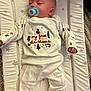 Jack is registered to the contest to win money with this photo: baby, infant, pacifier, onesie, christmas, holiday, star_pattern, changing_pad, white_clothing, cute, festive, sleepwear, child, indoor, soft_lighting, toddler, newborn, holiday_clothes, peaceful, portrait