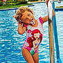 Aria a rejoint le concours — aidez-le/la à gagner de superbes lots ! child, girl, swimsuit, pool, water, ladder, curly_hair, blue_eyes, pacifier, playful, summer, vacation, outdoor, holiday, smiling, cute, cartoon_character, ariel, little_mermaid, fun