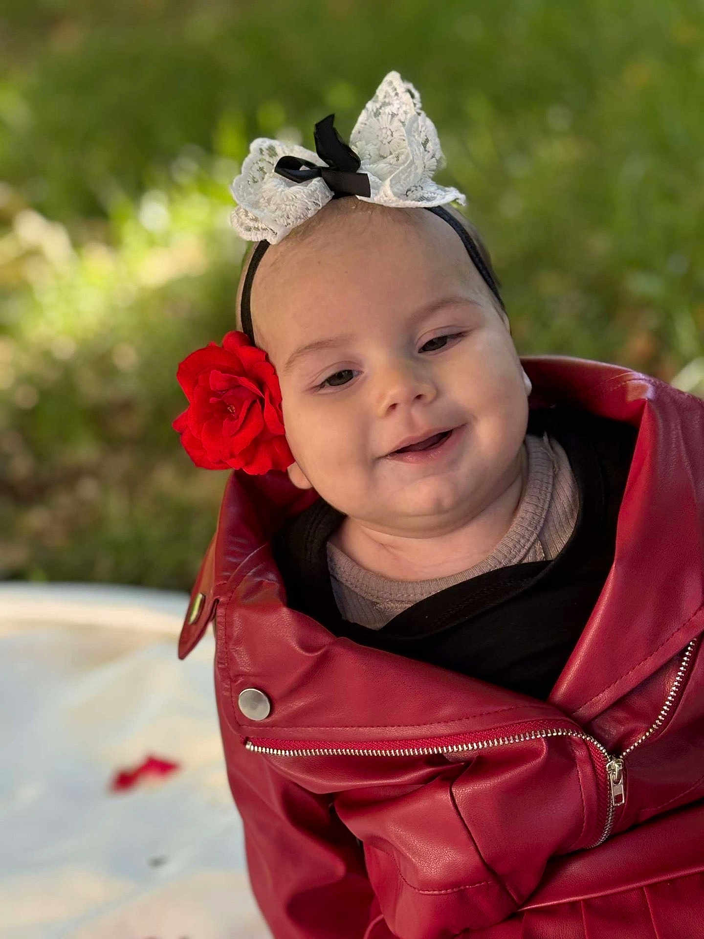 Aila participe au concours pour gagner de l'argent avec cette photo : baby, child, face, smile, red_jacket, flower, headband, outdoor, greenery, portrait, cute, happy, infant, fashion, closeup, baby_clothing, head_accessory, nature, soft_light, sitting