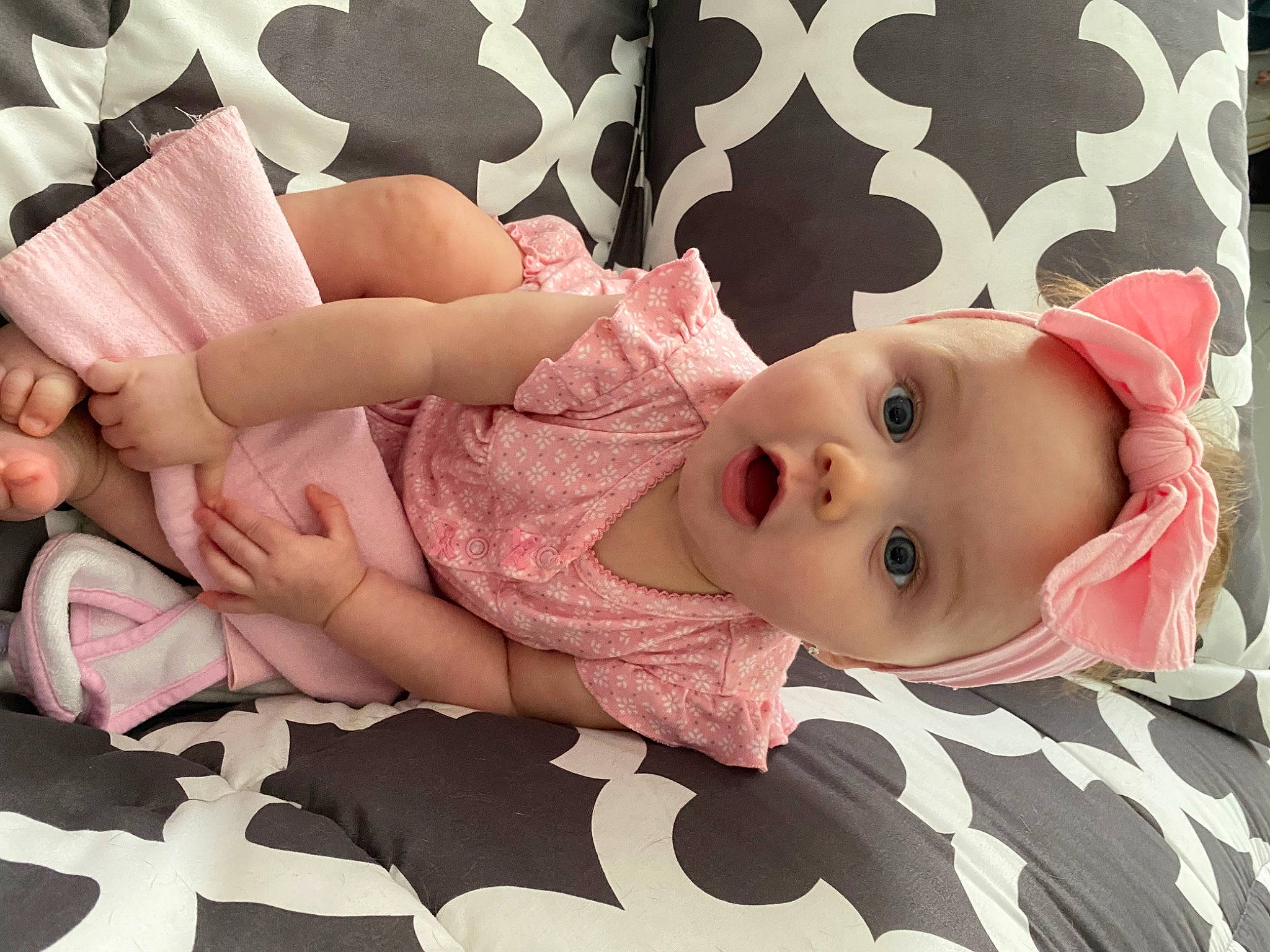 Sienna is registered to the contest to win money with this photo: arm, baby, baby_toddler_clothing, cheek, child, clothing, comfort, eye, face, facial_expression, head, headgear, headwear, human_body, linens, pattern, person, pink, skin, sleeve