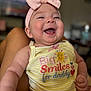 baby, infant, smiling, happy, headband, bow, yellow_stripes, clothing, portrait, cute, child, skin, face, arms, legs, sitting, indoors, blurred_background, person, joy