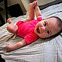 Journie joined the competition — help win amazing prizes! baby, infant, smiling, pink_onesie, bed, sheet, indoor, happy, face, legs, kicking, person, child, cute, lying_down, head, room, furniture, home, joyful