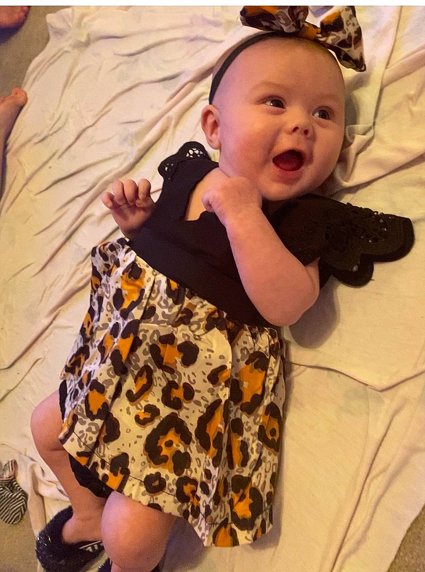 Adaleigh is registered to the contest to win money with this photo: baby, baby_toddler_clothing, child, comfort, eye, face, happy, head, human_leg, iris, linens, pattern, person, sitting, skin, sleeve, smile, t_shirt, textile, thigh