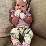 baby, beige, bow, child, couch, cozy, cute, floral_pants, hands, happy, headband, indoor, infant, mittens, portrait, purple_clothing, sitting, smiling, soft_lighting, young