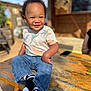 toddler, child, smile, jeans, tshirt, dinosaur_print, curly_hair, outdoor, wooden_table, sunlight, happy, portrait, sitting, casual_clothing, black_socks, nike_logo, daytime, blurred_background, cute, person