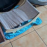 Chouquette a rejoint le concours — aidez-le/la à gagner de superbes lots ! cat, scratching_post, pet_bed, tile_floor, blue_mat, black_and_white_cat, indoor, animal, curious, hiding, wooden_frame, fabric, cozy, playful, home, feline, pet_accessory, resting_place, floor, small_animal