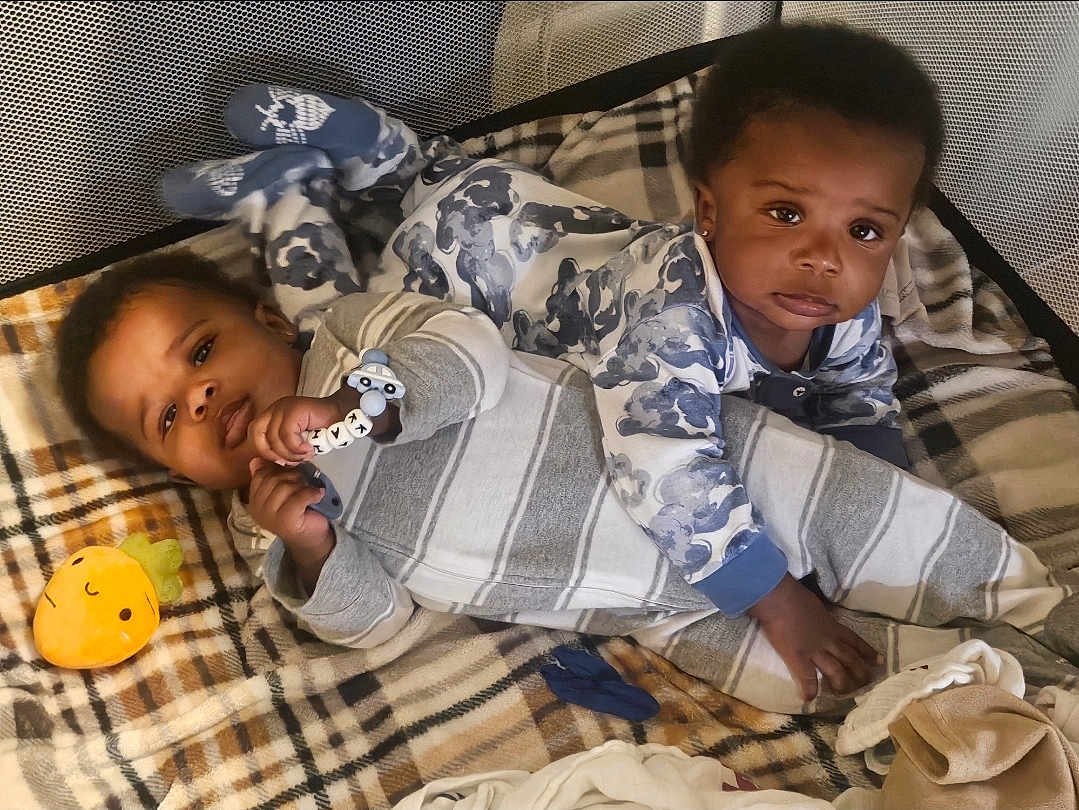 Kai'Ir And Kaidin is registered to the contest to win money with this photo: baby, babies, child, infant, playpen, blanket, pajamas, toy, plaid, indoor, cute, sleepwear, lying_down, face, expression, soft_lighting, comfort, childhood, adorable, young