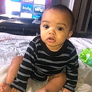 Dayvion is registered to the contest to win money with this photo: baby, child, striped_sweater, bed, television, apps, curious, indoor, person, face, wide_eyes, sitting, foot, hand, blanket, room, furniture, technology, expression, young