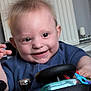 Martin joined the competition — help win amazing prizes! baby, child, smile, happy, toy, steering_wheel, indoor, radiator, clothing, person, face, hand, play, cute, infant, young_child, joy, expression, hair, closeup