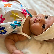 Arya participe au concours pour gagner de l'argent avec cette photo : adorable, arm, baby, child, closeup, clothing, cute, expression, face, flower_pattern, head, headband, indoors, infant, lying_down, portrait, skin, sleepwear, soft_blanket, young