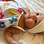 adorable, arm, baby, child, closeup, clothing, cute, expression, face, flower_pattern, head, headband, indoors, infant, lying_down, portrait, skin, sleepwear, soft_blanket, young