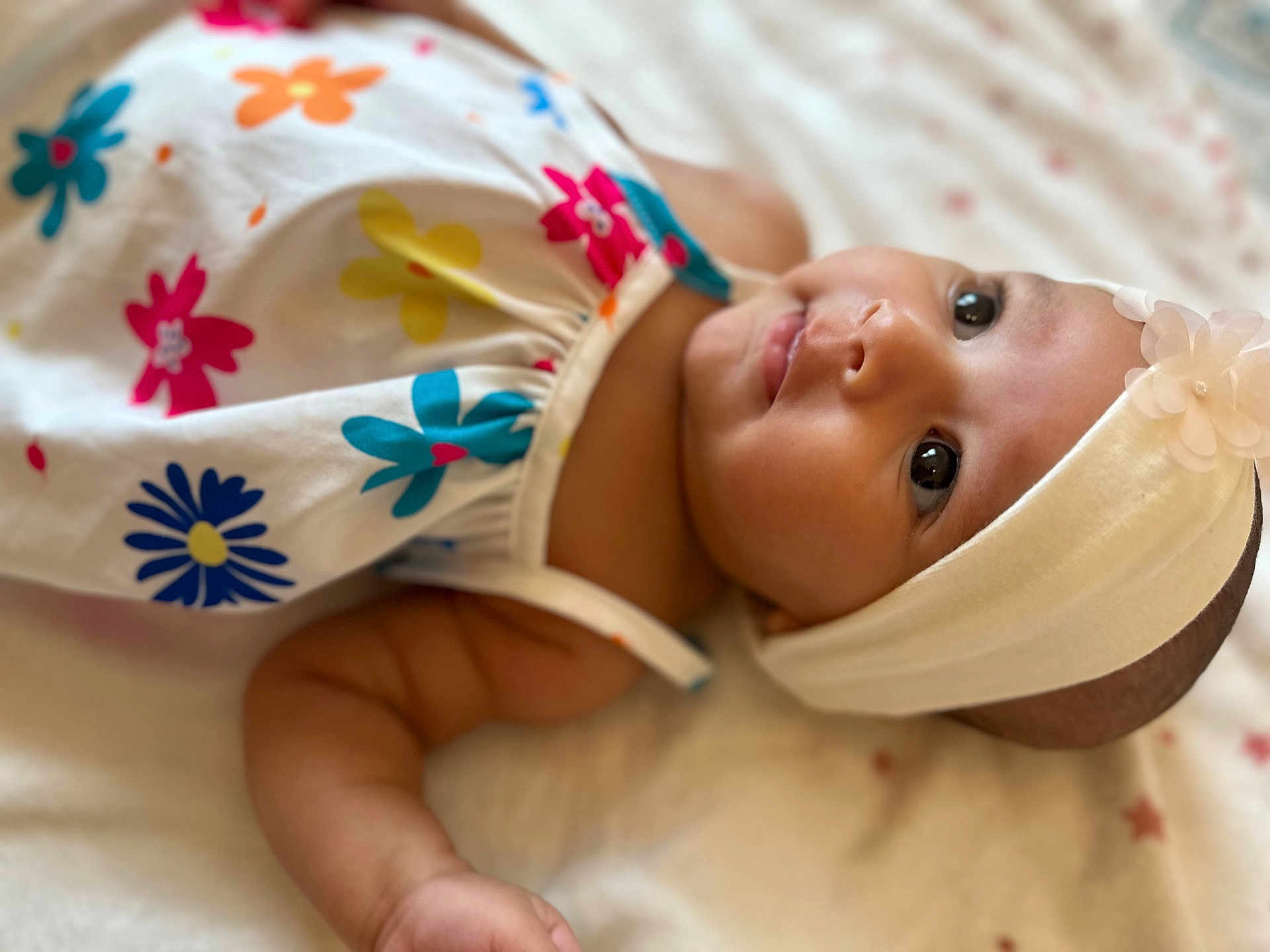 Arya participe au concours pour gagner de l'argent avec cette photo : adorable, arm, baby, child, closeup, clothing, cute, expression, face, flower_pattern, head, headband, indoors, infant, lying_down, portrait, skin, sleepwear, soft_blanket, young