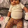 Feliciana is registered to the contest to win money with this photo: baby, infant, child, bed, blanket, clothing, mittens, pacifier, patterned_bedspread, onesie, leopard_print, bow, cute, lying_down, soft_toys, portrait, indoors, person, smiling, cozy