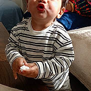 Muhammad joined the competition — help win amazing prizes! toddler, child, striped_shirt, funny_face, puckered_lips, tissue, wooden_table, embroidered_cloth, indoor, person, smile, adult, colorful_clothing, couch, home, light, shadow, curly_hair, sitting, happy