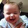 Aurora is registered to the contest to win money with this photo: adult, arm, baby, blanket, candid, child, close_up, clothing, eyes, face, happy, home, indoor, infant, laughing, mouth, onesie, portrait, sitting, smiling