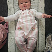 Aurora is registered to the contest to win money with this photo: baby, child, infant, smiling, portrait, lying_down, play_seat, padded_mat, striped_clothing, pink_clothing, overalls, long_sleeves, socks, outstretched_arms, indoor, household, shoes, bag, carpet, happy
