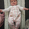 baby, child, infant, smiling, portrait, lying_down, play_seat, padded_mat, striped_clothing, pink_clothing, overalls, long_sleeves, socks, outstretched_arms, indoor, household, shoes, bag, carpet, happy