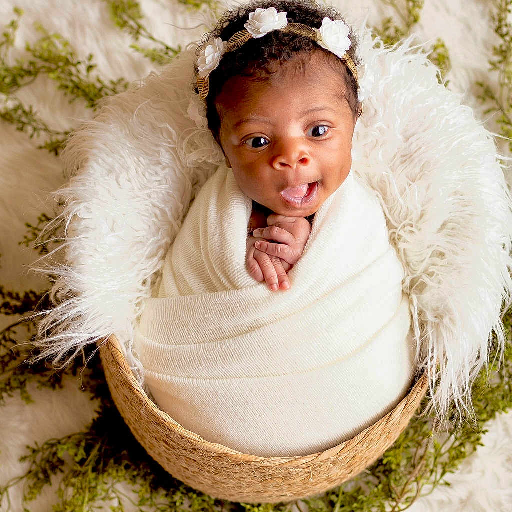 Kenzley joined the competition — help win amazing prizes! baby, background, basket, blanket, cozy, curly_hair, cute, expression, flower, greenery, hands, headband, indoor, infant, newborn, portrait, soft_texture, white, wide_eyes, wrapped