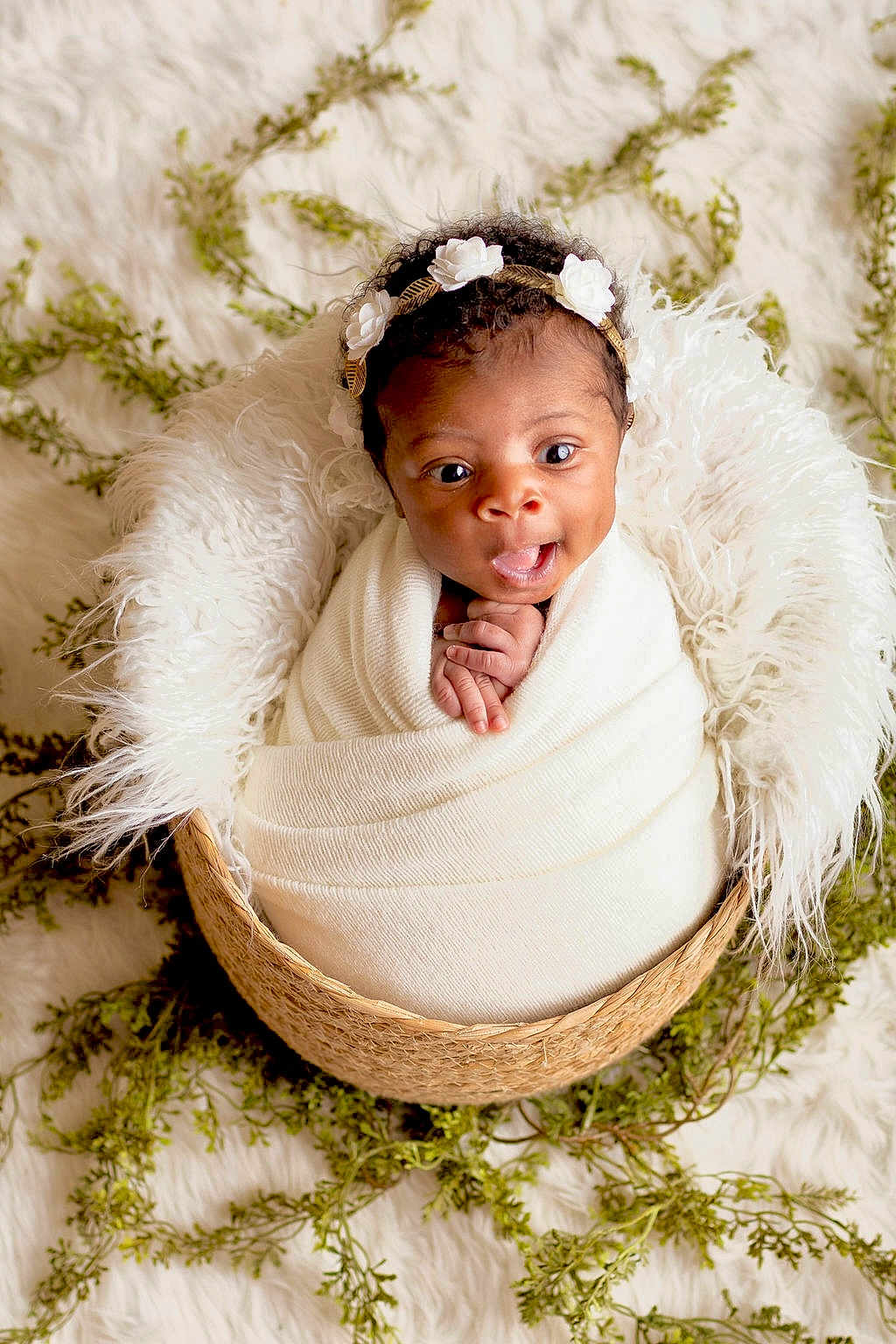 Kenzley joined the competition — help win amazing prizes! baby, infant, wrapped, blanket, basket, headband, flower, curly_hair, expression, wide_eyes, hands, white, cozy, soft_texture, greenery, background, cute, portrait, newborn, indoor
