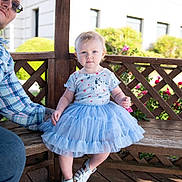 Olivia joined the competition — help win amazing prizes! toddler, child, blue_dress, bench, wooden_structure, outdoor, man, glasses, sunlight, flowers, greenery, curious_expression, sitting, footwear, casual_clothing, portrait, daylight, playful_adult, nature, summer