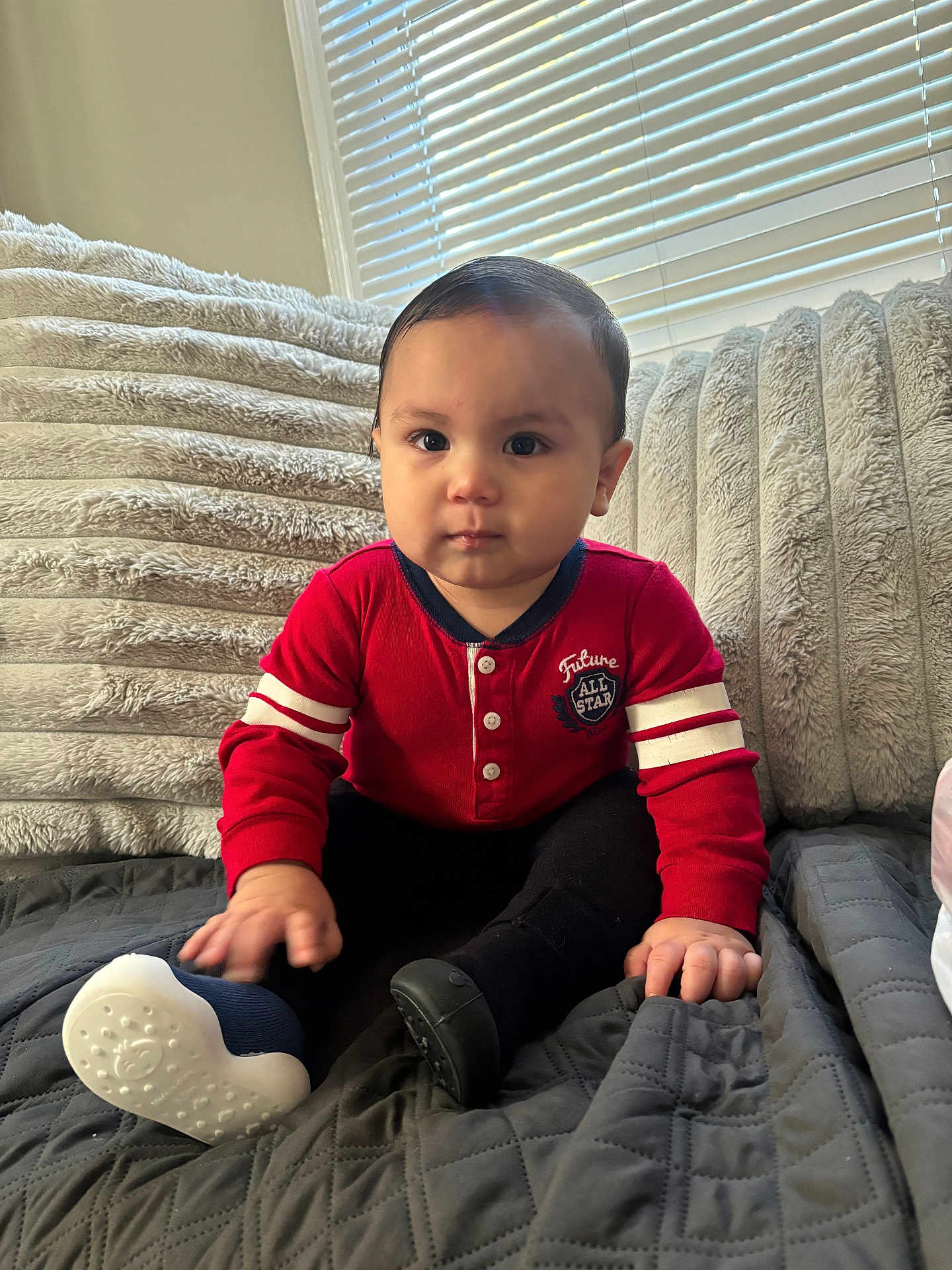 Josselyn Johanna joined the competition — help win amazing prizes! baby, child, red_sweater, black_pants, soft_toys, cushions, window_blinds, gray_quilt, indoor, seated, curious_expression, natural_light, hand, footwear, plush, portrait, cozy, home, cute, young_child