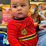 toddler, child, red_clothing, firefighter_outfit, indoor, person, curious, cheeks, face, baby, portrait, snacks, grocery_store, sitting, cute, young_child, holding, casual, bright_colors, background_blur