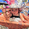 aisle, baby, black_tank_top, cart, child, colorful, cowboy_hat, elephant_toy, floral_pattern, hat, indoor, infant, playful, plush_toy, portrait, retail_store, shopping, shopping_cart, smiling, supermarket