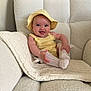 baby, child, smile, yellow_hat, yellow_outfit, socks, knitted_blanket, white_couch, happy, indoor, person, cute, infant, cozy, portrait, sitting, soft_texture, blue_eyes, hand, legs
