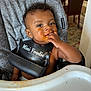 Isaiah is registered to the contest to win money with this photo: baby, bib, child, clothing, curly_hair, cute, eating, feeding_time, food, fun, hand, happy, high_chair, indoor, infant, kitchen, messy_face, portrait, smiling, toddler
