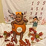baby, pumpkin, orange_bow, autumn_leaves, fall_decor, smiling, eight_months, calendar, scarecrow, decorative_pumpkins, infant, holiday_theme, cute, sitting, indoors, celebration, festive, child, portrait, seasonal