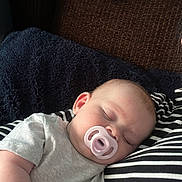 Amelia joined the competition — help win amazing prizes! baby, sleeping, pacifier, striped_clothing, blanket, couch, cozy, infant, rest, comfort, child, indoor, relaxation, face, head, soft_texture, peaceful, napping, person, toddler