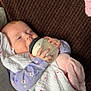 Amelia is registered to the contest to win money with this photo: baby, bottle, blanket, couch, drink, face, floral, hand, infant, milk, person, plush_toy, purple_clothing, relaxing, sleepy, soft_texture, white_blanket, wrapped, young_child, indoors