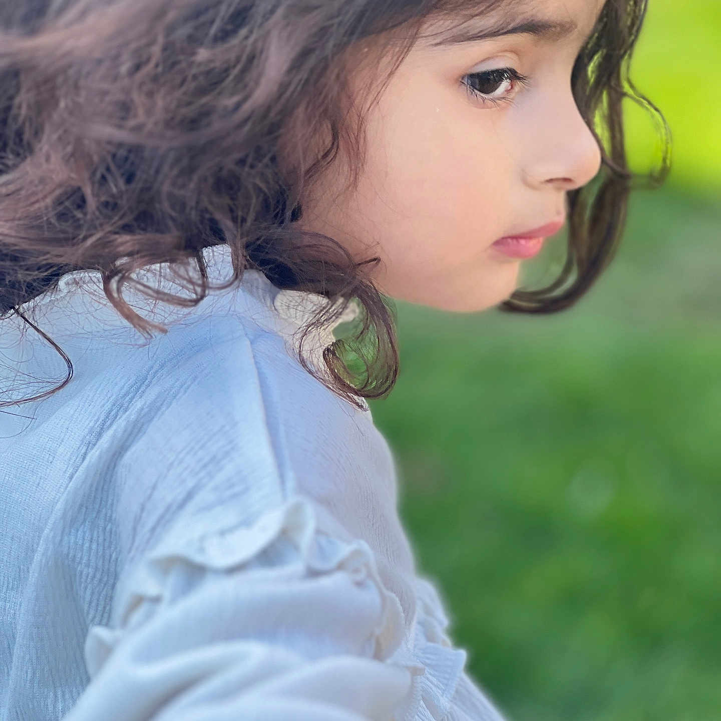 Sajal is registered to the contest to win money with this photo: casual, child, closeup, curly_hair, cute, face, fashion, green_background, natural_light, outdoor, person, portrait, profile, serene, side_view, skin, soft_focus, thoughtful, white_clothing, young