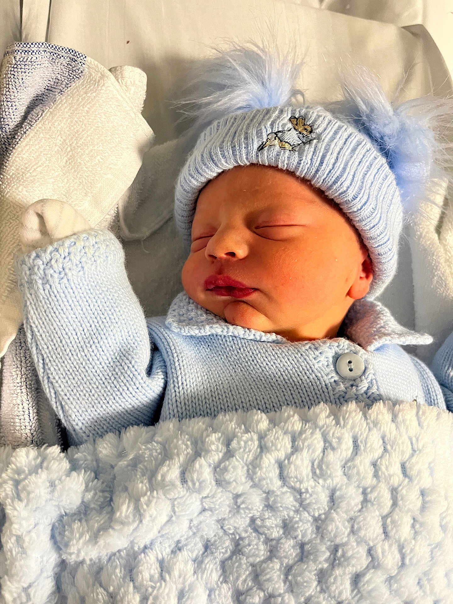 Tommy is registered to the contest to win money with this photo: newborn, baby, sleeping, blue_hat, knitwear, blanket, soft_texture, cozy, infant, cute, child, portrait, indoor, peaceful, wrapped, warm, pom_poms, headwear, close_up, resting