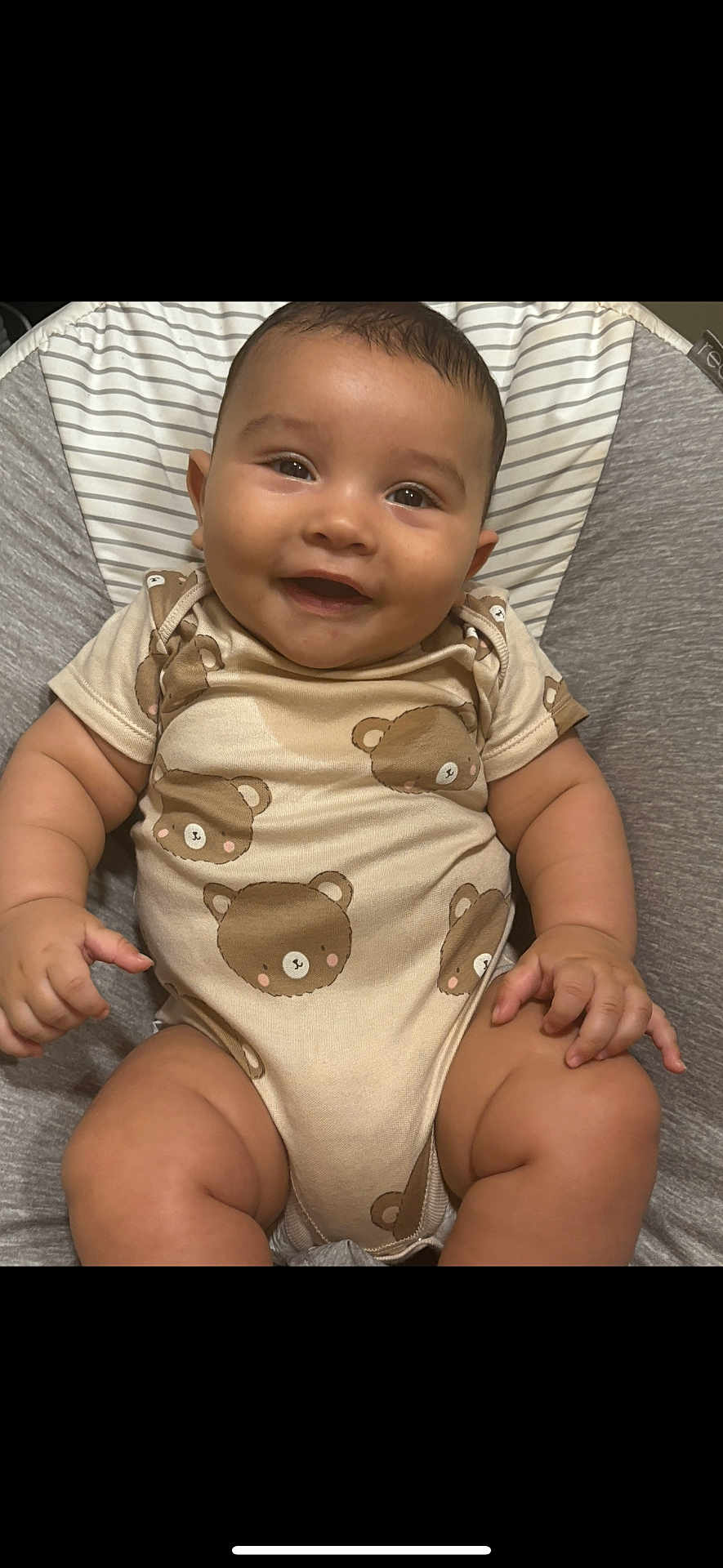 Leo is registered to the contest to win money with this photo: baby, smiling, infant, onesie, bear_pattern, cushion, seat, happy, child, cute, portrait, skin, chubby, sitting, indoors, comfortable, young, head, face, expression