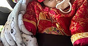 Agustin is registered to the contest to win money with this photo: adorable, baby, blanket, car_seat, child, cozy, cute, gold_embroidery, hat, indoors, infant, pacifier, patterned_blanket, portrait, red_clothing, resting, seatbelt, sleeping, traditional_clothing, young_child