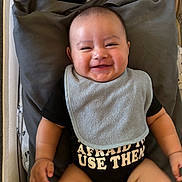 Agustin joined the competition — help win amazing prizes! baby, baby_bib, baby_clothes, bib, black_clothing, child, cow_plush, cushion, cute, face, happy, indoors, infant, lying_down, onesie, person, pillow, plush_toy, smiling, soft_toy