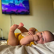 Agustin joined the competition — help win amazing prizes! baby, infant, bed, blanket, yellow_clothing, hand, foot, face, lying_down, indoors, television, blurred_background, cute, chubby, skin, person, resting, sleepy, red_bracelet, cozy