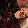 person, cat, black_cat, animal, pet, face_filter, dog_filter, lying_down, indoor, bed, pillow, casual, young_adult, relaxed, closeup, selfie, hair, clothing, tshirt, colorful_background