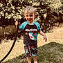 Jameson joined the competition — help win amazing prizes! child, toddler, boy, barefoot, wet_hair, garden_hose, grass, outdoor, summer, smiling, happy, swimwear, shorts, shirt, nature, sunlight, greenery, playing, water, casual