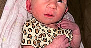 Bella is registered to the contest to win money with this photo: baby, blanket, clothing, cute, expression, face, hand, human, indoors, infant, leopard_print, lying_down, newborn, person, portrait, skin, sleepwear, small, soft_texture, young_child