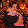 baby, infant, adult, parent, 抱抱, portrait, smiling, sleepy, pacifier, pink_clothing, pajamas, family, halloween, pumpkin, jack_o_lantern, skeleton, bats, autumn, string_lights, indoor